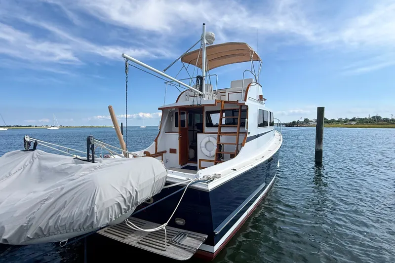 Slide: The Image of 1987 Wilbur Flybridge Cruiser docked on calm water under a clear sky. - 12