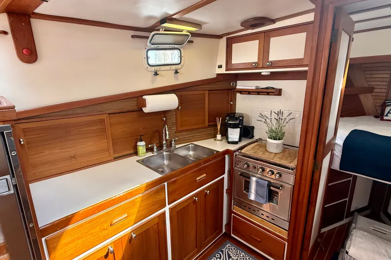 Slide: The Image of 1987 Wilbur Flybridge Cruiser kitchen with wood cabinetry, stainless steel sink, and compact stove. - 50