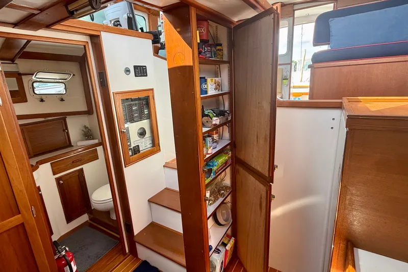 Slide: The Image of 1987 Wilbur Flybridge Cruiser interior with wooden cabinetry, pantry, and compact bathroom. - 51