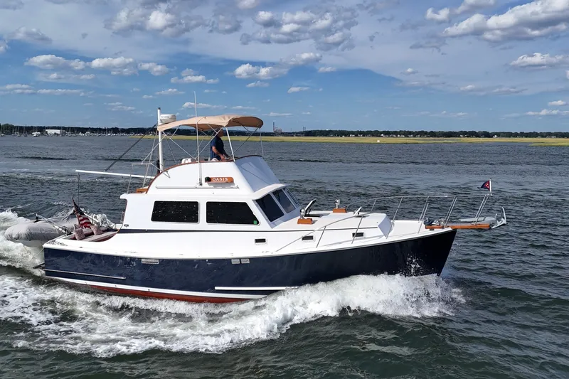 Slide: The Image of 1987 Wilbur Flybridge Cruiser navigating through calm waters under a partly cloudy sky. - 1
