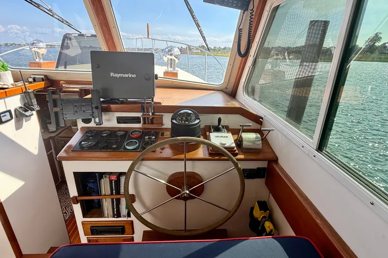 Slide: The Image of 1987 Wilbur Flybridge Cruiser helm with Raymarine equipment, overlooking serene waters. - 43