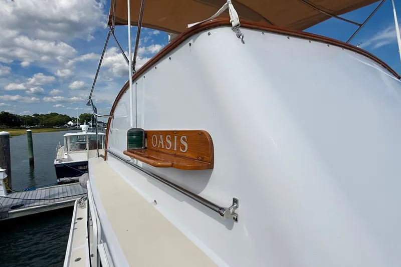 Slide: The Image of 1987 Wilbur Flybridge Cruiser "Oasis" docked under a sunny sky. - 28