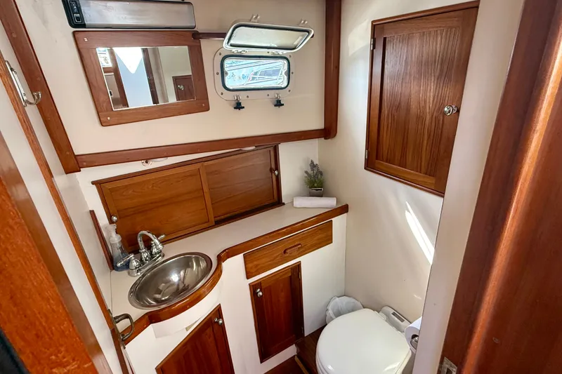 Slide: The Image of 1987 Wilbur Flybridge Cruiser bathroom with wooden cabinetry, stainless steel sink, and porthole window. - 52