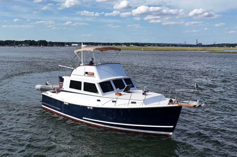 Slide: The Image of 1987 Wilbur Flybridge Cruiser on calm waters under a partly cloudy sky. - 5