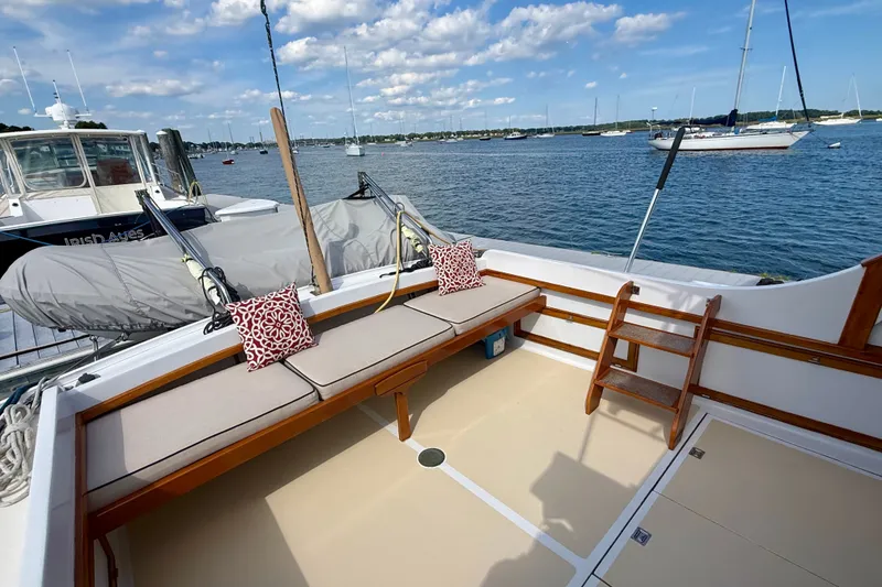 Slide: The Image of 1987 Wilbur Flybridge Cruiser deck with seating, ladder, and scenic harbor view. - 17