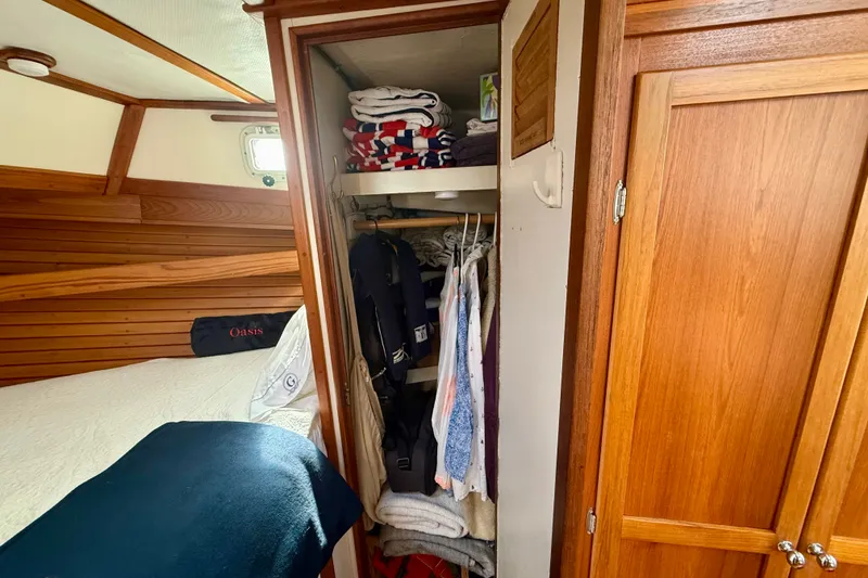 Slide: The Image of 1987 Wilbur Flybridge Cruiser cabin with wooden interior and organized closet space. - 57