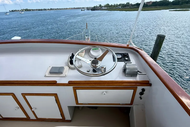 Slide: The Image of 1987 Wilbur Flybridge Cruiser helm with wooden trim, overlooking serene waters. - 35