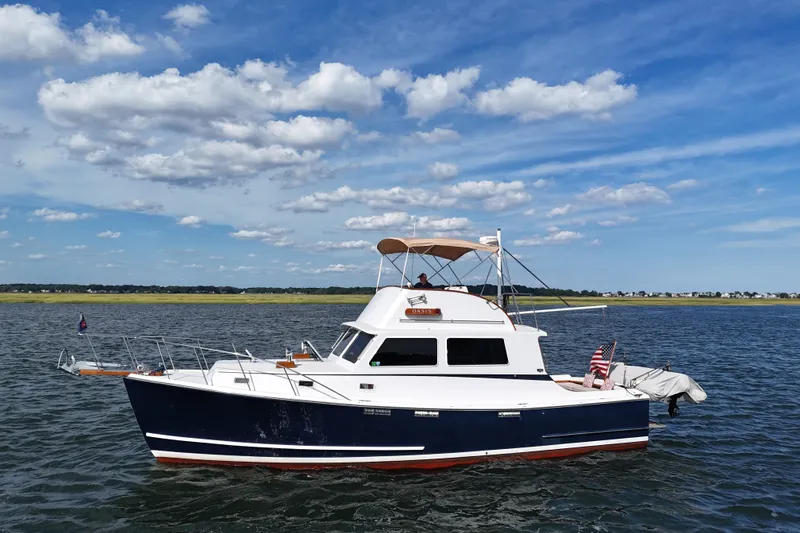 Slide: The Image of 1987 Wilbur Flybridge Cruiser on calm water under a blue sky with clouds. - 3