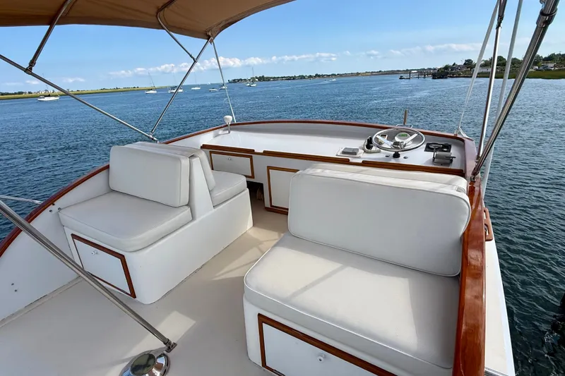 Slide: The Image of 1987 Wilbur Flybridge Cruiser with white seating and helm, overlooking calm waters. - 31