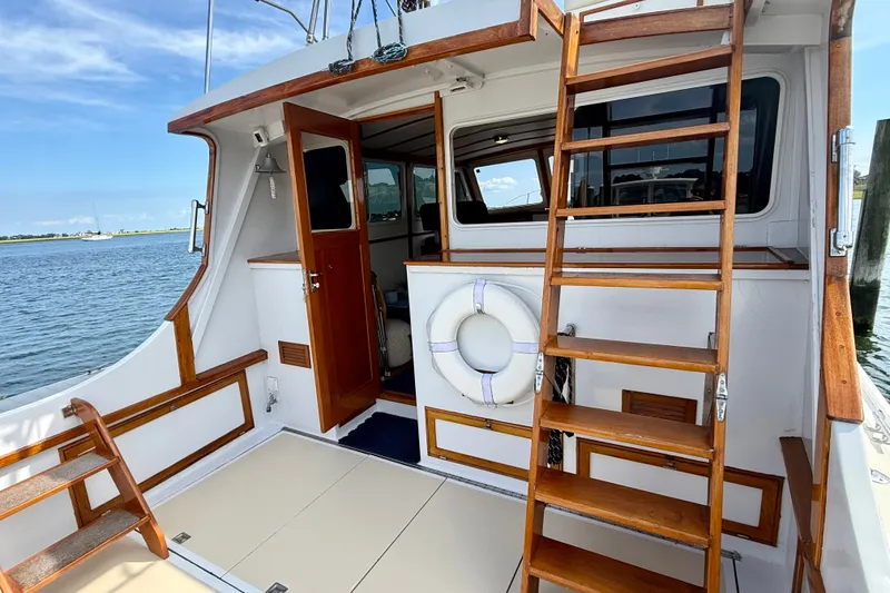 Slide: The Image of 1987 Wilbur Flybridge Cruiser with wooden accents, docked by the water. - 13