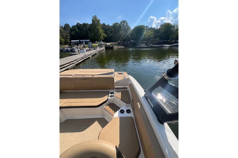 Slide: The Image of 2022 Sea Ray SPX 210 boat interior with tan seating, docked by a scenic lake. - 31