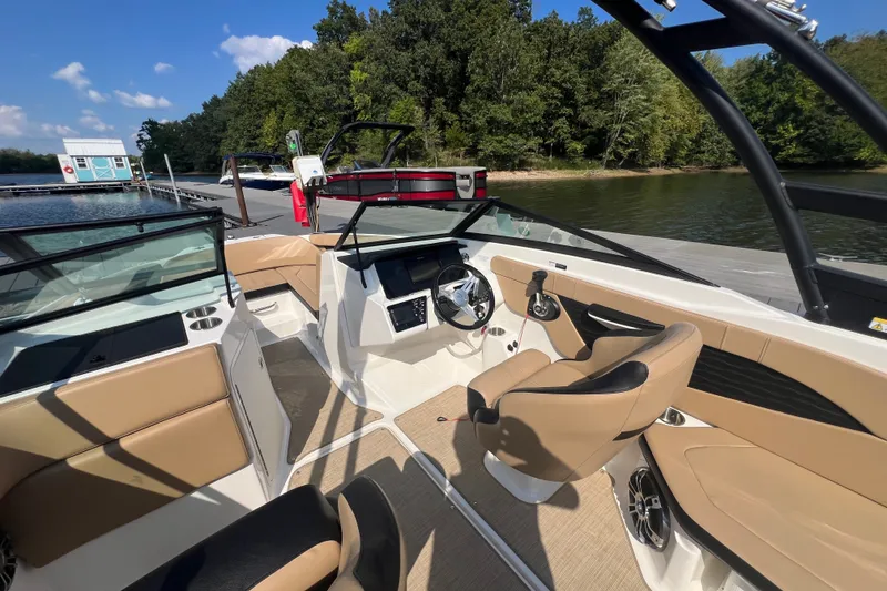 Slide: The Image of 2022 Sea Ray SPX 210 boat interior with tan seating, steering wheel, and lake view. - 17