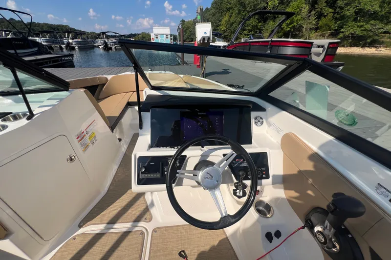 Slide: The Image of 2022 Sea Ray SPX 210 boat cockpit with steering wheel and dashboard, docked at marina. - 20