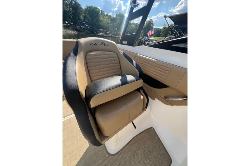 Slide: The Image of 2022 Sea Ray SPX 210 boat seat with tan and black upholstery, dockside view. - 43