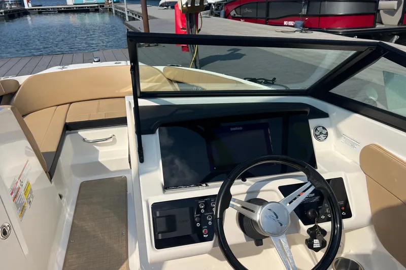 Slide: The Image of 2022 Sea Ray SPX 210 boat interior with steering wheel and dashboard at a marina. - 26