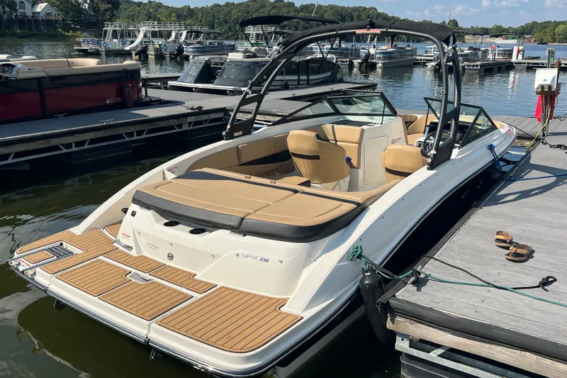 Slide: The Image of 2022 Sea Ray SPX 210 boat docked at marina with tan seating and sleek design. - 15