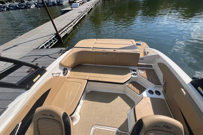 Slide: The Image of 2022 Sea Ray SPX 210 boat interior with tan seating, docked by the water. - 22