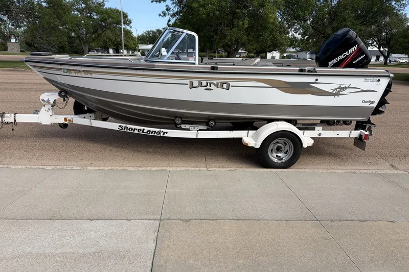 The Image of 2003 Lund 1850 Tyee OB boat on ShoreLand'r trailer, parked outdoors. - 0