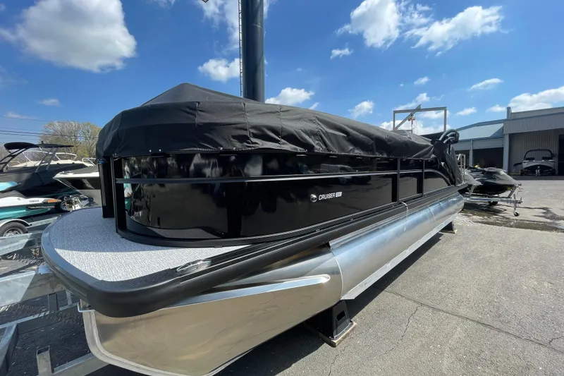 Slide: The Image of 2026 Harris Cruiser 230 SLDH pontoon boat with cover, parked outdoors under blue sky. - 21