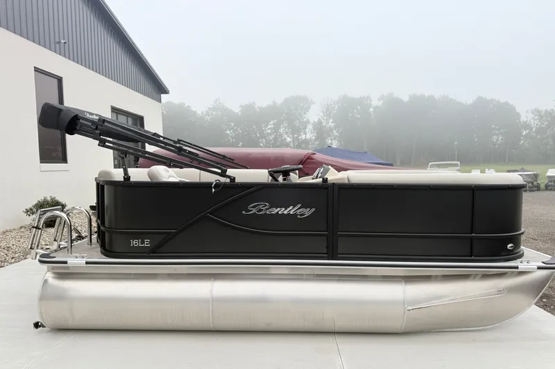 The Image of 2027 Bentley Pontoons LE 160 CR pontoon boat, black exterior, parked outdoors on a foggy day. - 1