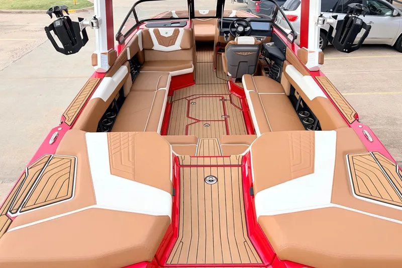 Slide: The Image of 2022 Nautique Super Air Nautique G25 interior with tan and white seating, red accents. - 9
