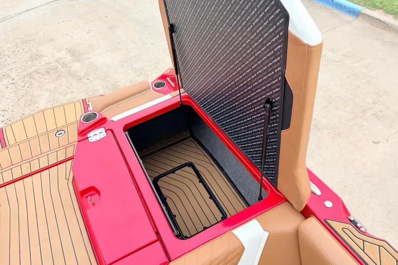 Slide: The Image of 2022 Nautique Super Air Nautique G25 storage compartment with open hatch, red and tan interior. - 45