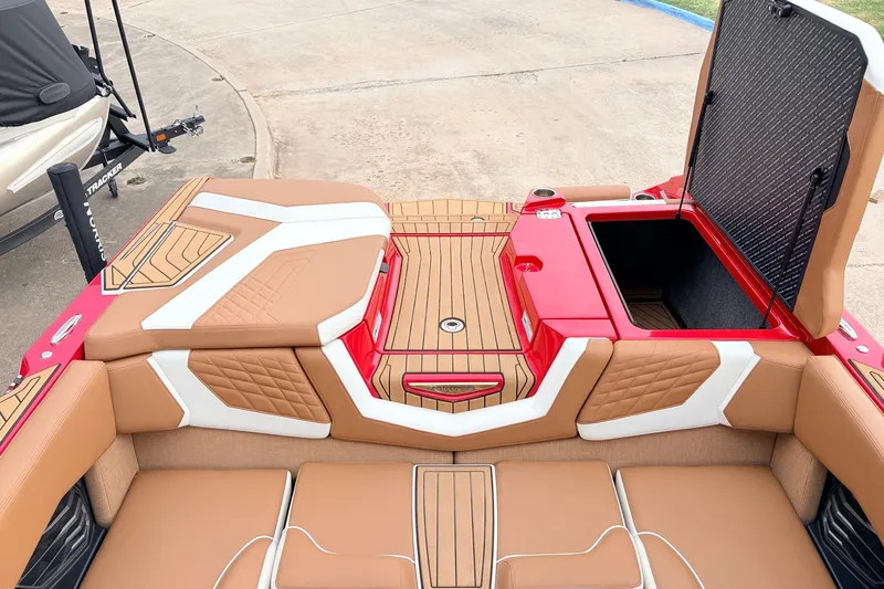 Slide: The Image of 2022 Nautique Super Air Nautique G25 boat interior with tan and white seating, open storage compartment. - 44