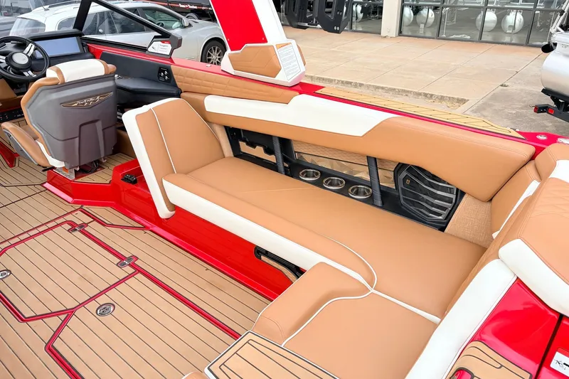 Slide: The Image of 2022 Nautique Super Air Nautique G25 interior with tan and red seating, cup holders, and steering wheel. - 36