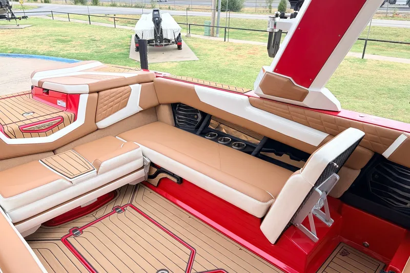 Slide: The Image of 2022 Nautique Super Air Nautique G25 interior with tan and red seating, cup holders, and deck. - 24
