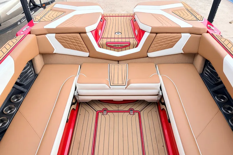 Slide: The Image of 2022 Nautique Super Air Nautique G25 interior with tan and white seating, red accents. - 27