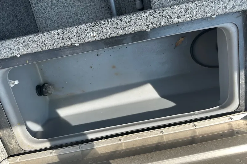 Slide: The Image of Bass Tracker Pro 16 boat storage compartment, 2021 model, with gray interior and carpeted edges. - 26