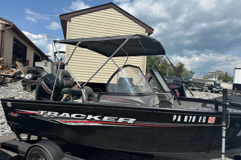 Slide: The Image of 2021 Bass Tracker Pro 16 boat with canopy, parked outdoors under cloudy sky. - 34