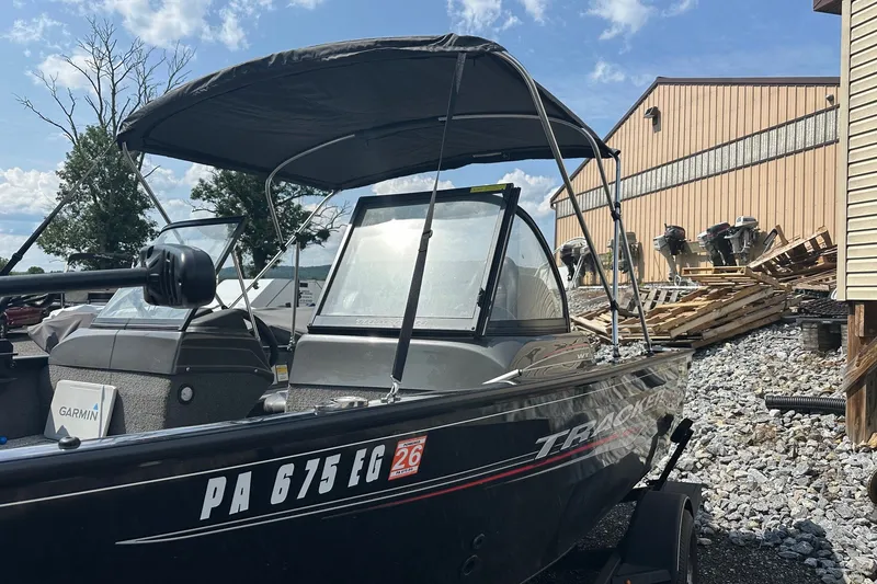 Slide: The Image of 2021 Bass Tracker Pro 16 boat with canopy, parked on gravel near a building. - 35