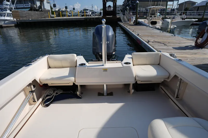 Slide: The Image of 2018 Grady-White Freedom 192 boat interior at dock, featuring cushioned seating and motor. - 15