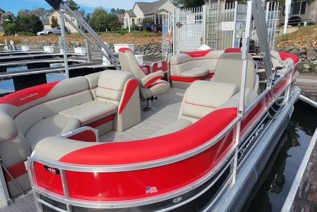 Slide: The Image of 2021 South Bay RSLE Tri Toon boat with red and beige seating at a marina. - 3