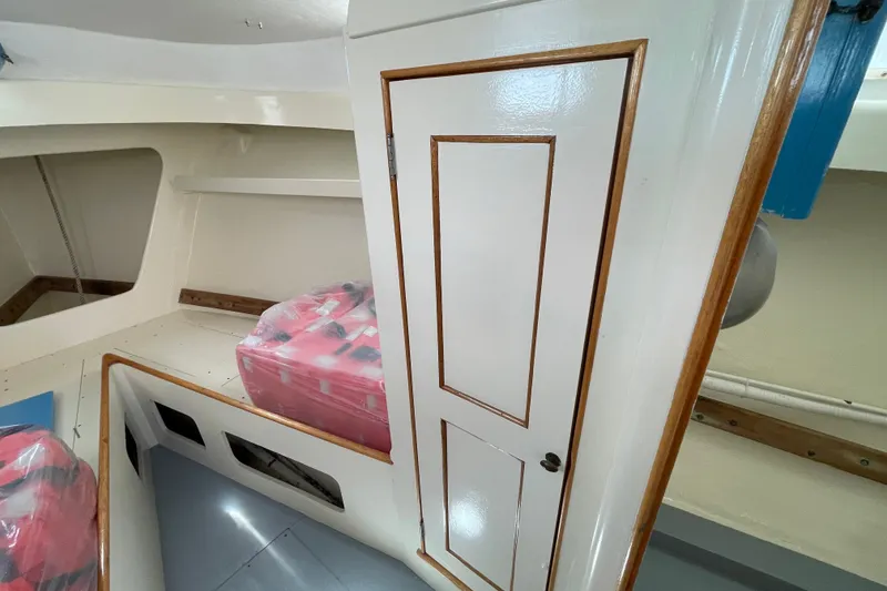 Slide: The Image of Interior of a 1966 Webbers Cove 34 boat, featuring a white door and storage area. - 43
