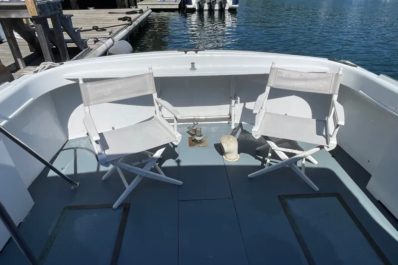Slide: The Image of Two white chairs on a 1966 Webbers Cove 34 boat deck by the water. - 27