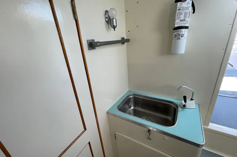 Slide: The Image of Compact sink area with fire extinguisher in a 1966 Webbers Cove 34 boat. - 45