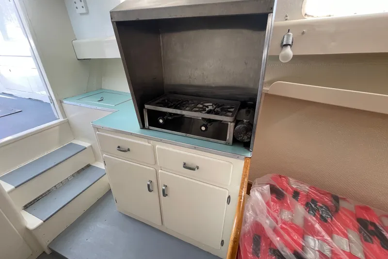 Slide: The Image of Interior of a 1966 Webbers Cove 34 boat featuring a compact kitchen with a stove. - 47
