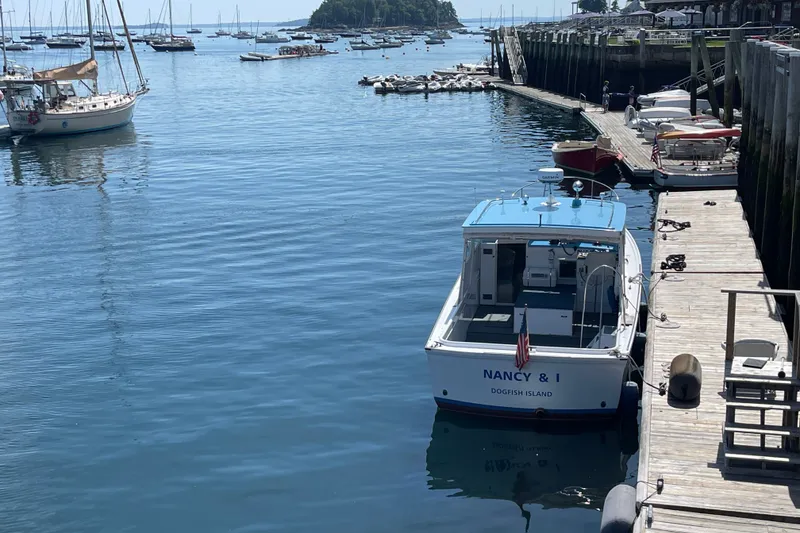 Slide: The Image of 1966 Webbers Cove 34 boat docked at a marina, surrounded by calm water and other vessels. - 18