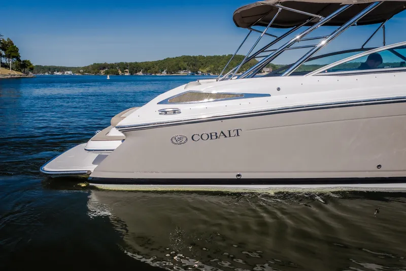 Slide: The Image of 2010 Cobalt 302 boat cruising on a serene lake under a clear blue sky. - 11