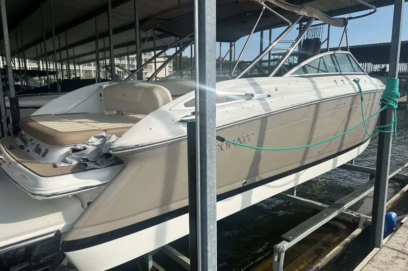 Slide: The Image of 2010 Cobalt 302 boat docked in a marina, side view with beige and white exterior. - 2