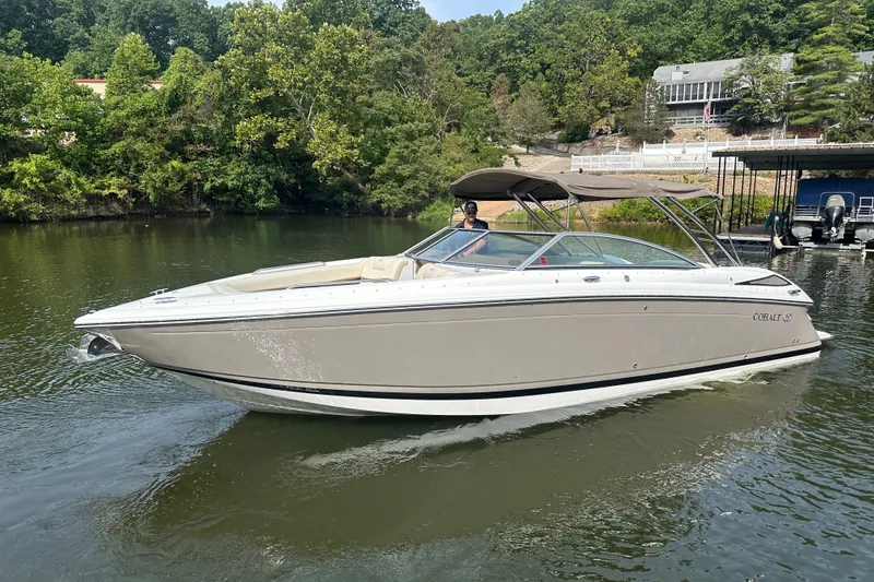 The Image of 2010 Cobalt 302 boat cruising on a serene lake with lush greenery. - 1