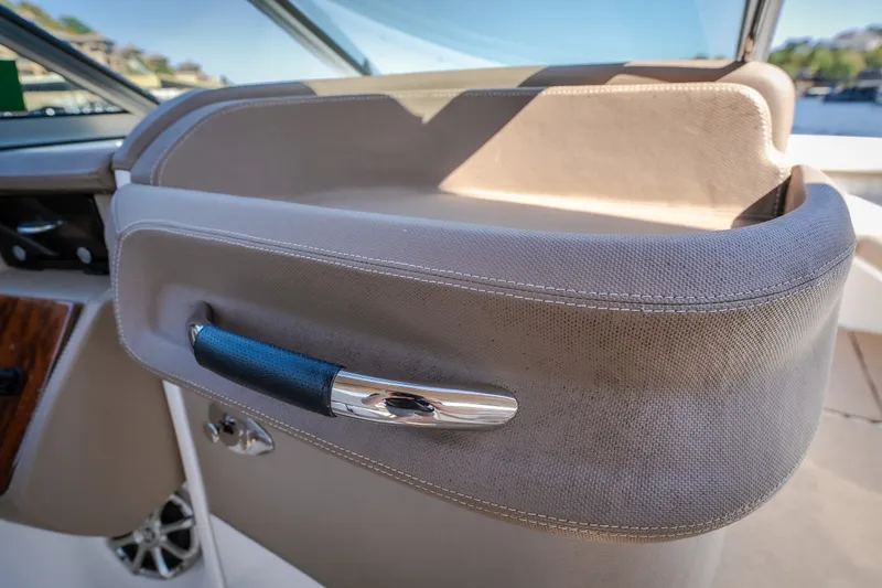 Slide: The Image of Interior detail of a 2010 Cobalt 302 boat, featuring a sleek handle and beige upholstery. - 6