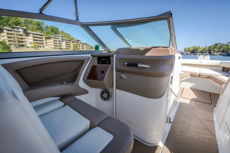 Slide: The Image of Interior of a 2010 Cobalt 302 boat with beige and white seating, near waterfront buildings. - 5