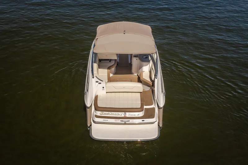 Slide: The Image of 2010 Cobalt 302 boat on calm water, rear view with beige seating and canopy. - 9