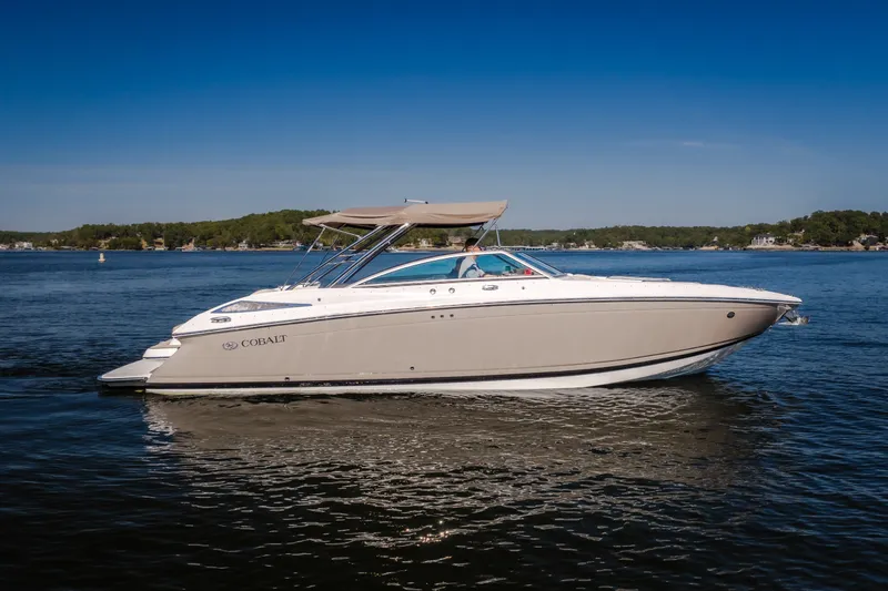 The Image of 2010 Cobalt 302 boat cruising on a serene lake under a clear blue sky. - 2