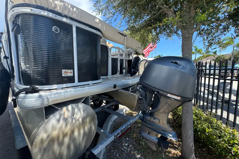 Slide: The Image of 2017 Godfrey Sweetwater Sunrise 22 pontoon boat with outboard motor, parked near a tree. - 18