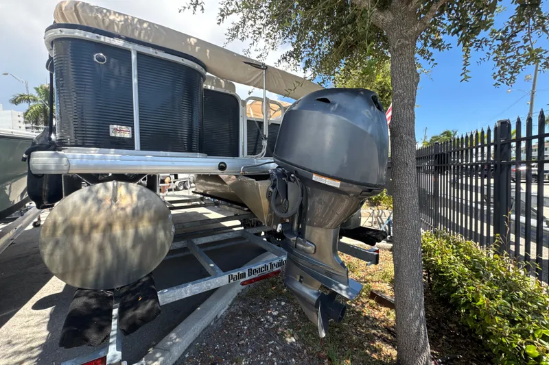 Slide: The Image of 2017 Godfrey Sweetwater Sunrise 22 pontoon boat on trailer, parked near a tree. - 19