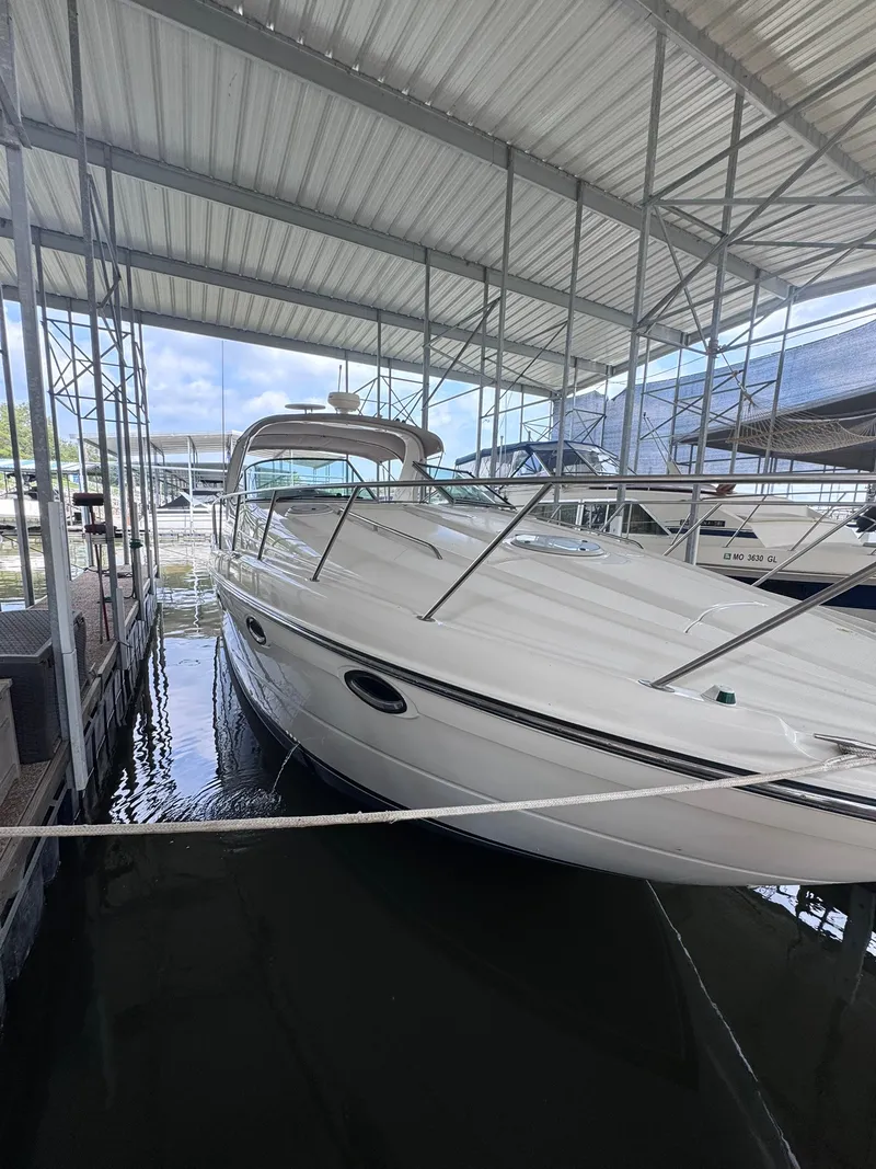Slide: The Image of A 2001 Maxum 3500 SCR docked in a covered marina. The white boat features a sleek design. - 2
